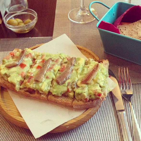wooden plate with avocado and anchovies on toast at vega 10 seville