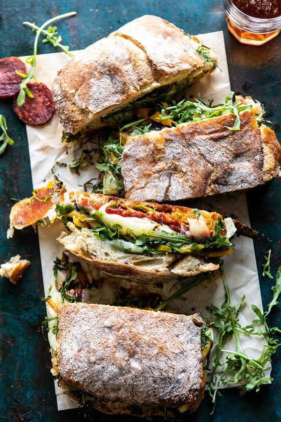 Crusty ciabatta bread, sandwiched with homemade Italian vinaigrette, spicy salami, salty prosciutto, fresh baby arugula, roasted peppers, provolone AND mozzarella. It's the easiest way to serve up a melty sandwich to a hungry group of guests. Perfect for your game day eats!