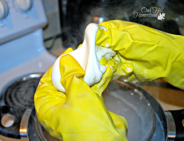 Stretching the warm mozzarella cheese curds while wearing yellow rubber gloves..