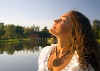Doğada bir göl kıyısında temiz havada gözleri kapalı nefes alan bir bayan