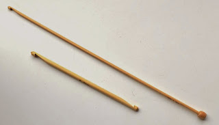 Two bamboo hooks photographed on the diagonal: (lower left) 6 mm diameter double-ended hook 15 cm long; (top right) 4 mm diameter tricot (Tunisian) hook 30 cm long. The head of the hook is at the top left and the stop is on the bottom right end.