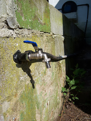 Salida de agua en pared exterior, instalación mediante tubo de goma.