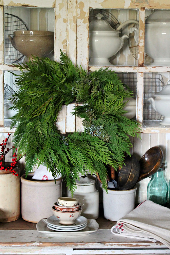 Small evergreen wreath hung in front of vintage cabinetry in the kitchen of Rusty Hinge