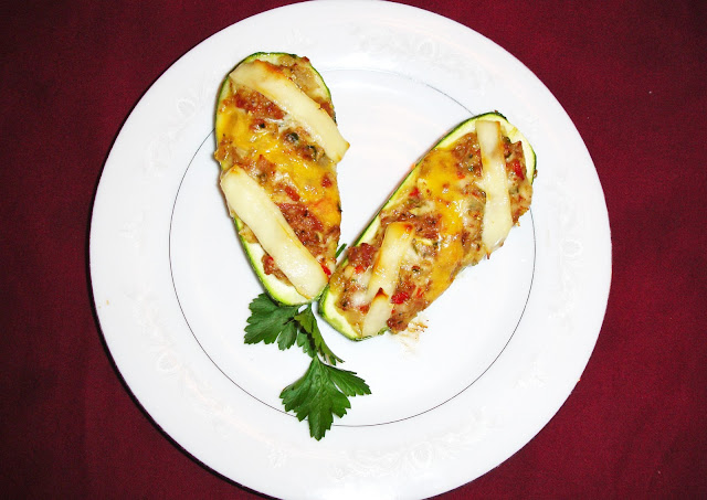 PORTIONS: 4 INGREDIENTS 4 zucchini, washed, cut in ½ length wise 8 oz. bacon cut thin sideway. 1 ½ cups diced onions 2 chopped garlic cloves  1/3 cup diced red peppers 2 tbsp. chopped parsley ½ tsp. salt 3 tbsp. bread crumbs 2 ½ oz. grated mozzarella cheese 3 oz. grated Roman or Parmesan cheese 3 slices cheddar cheese, cut in strips length wise 3 slices mozzarella cheese, cut in strips length wise PREPARATION With an spoon remove the pulp of the center of the zucchini. Making the shape of a canoe. Save the pulp and chop. In a hot pan, place the bacon and cook it until crispy. Add onions, garlic and cook. Add zucchini, peppers, salt, parsley, cook for a minute. Add bread crumbs, grated mozzarella and Parmesan cheese. Stuff the zucchini with the mix. Decorate the top with the strips of cheddar and mozzarella cheese interchanging colors.  Preheat the oven a at 425° F - 220° C. Cook for about 12 minutes. Zucchinis should be cooked al dente.