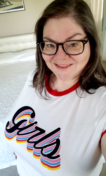image of me in a white t-shirt with red collar and cuff, with 'Girls' in swirly letters outlined with colorful rings