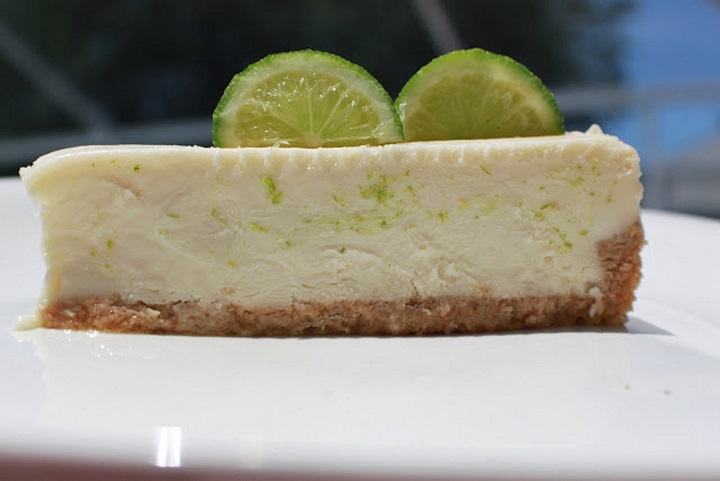 this is a slice of margarita cheesecake on a white plate with slices of lime on top.