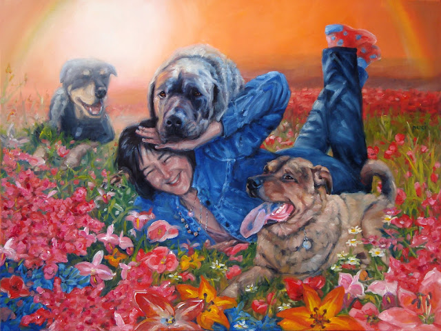 happy woman with her 3 dogs all around her ina field of flowers with rainbow