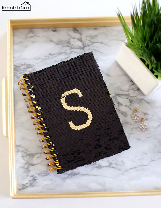Black and gold sequin covered notebook on modern tray