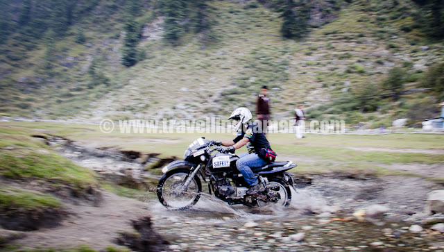 Camping at Kullu Sarahan, some trekking to nearby waterfalls, Cricket on lush green ground and some bike stunts around water bodies... It was a wonderful day at Kullu Sarahan and probably I would not be able to write about amazing bike stunts by Aneesh !!!Basically it started with some random chit-chat while coming back from a short trek to nearby waterfall... Aneesh came on his bike and was doing some crazy stuff on the way... Like crossing a thin wooden bridge with his bike, irritating bulls who started chasing him later etc..Later some of the folks asked him to show some stunts and he was very happy about it :) ... It seemed he was already waiting for this request :)As we said that we will be shooting photographs and videos of your stunts, he thought of washing his bike in style :) ... We shall be able to share those videos soon !!!It was important to wash it well, so multiple rounds in this water stream were required...After washing his bike, Aneesh thought of writing his name on this lush green ground at Kullu Sarahan... Video embedded in the end is about the same activity of writing name on ground !!! Just check out this warm-up session !!!Suddenly he realized that helmet and other required equipments were missing and he should not proceed with stunting exercise without those... A quick ride till camp and coming back took 8 odd minutes and everyone was excited to see real action !!!Sarahan school was open during the day and classes were going on in open area outside school boundary from where whole Sarahan ground was visible... All school children along with their teachers were looking towards us and somehow we were feeling bad about it... Bust suddenly teachers thought of freeing up all the students for some time and watch the action in their village !!! You can one boy and a girl in the background of photograph above...While going up, he drove bike on this bridge but somehow he was cautious in front of my Travelling Camera :) ... which was quite obvious ;)In case you don't see much energy and adventure in these shots, that's pure fault of my photography as this whole session was mind blowing and his bike was flying like anything... Even I feel that I could not capture it well...Suddenly whole environment changed in Sarahan... People form village started coming to this ground and few folks who used to play cricket also thought of coming to this ground in advance... Whole day in Kullu Sarahan was full of fun and masti ... And we enjoyed each moment of it...Chief Bike Marshal and MTB offical Mr. Aneesh Ariborne Awasthi, showing off his gadgets :)Anyway Aneesh is currently looking for sponsorship to get new bike and here he is showing everything on his Pulsar... As per knowledge I have, he has won many competitive bike rallies with same bike while other competitors have been coming with imported bikes mainly used in such rallies...There were lots of water streams in this ground, but the whole session was smooth and enjoyable... and  I pray to god that Himachal Government don't see this ground, as they are spoiling some of the natural beauties by building sports complexes on top of them... I don't think it's right...In Feb 2011, Aneesh had made a record of reaching Hatu peak with his bike when whole area was covered with snow... If you have missed, I strongly recommend you to see this story about the amazing Climb @ Climbing, Falling, Stumbling, and Crawling to theHatuTemple : MISSION HATU PEAK (21 FEBRUARY 2011Lot more action to come... So just keep watching this place for more fun and Stunts !!!All these photographs were clicked during Mountain Terrain Biking event in Himachal. It was forth day of the event and a rest day at Sarahan.