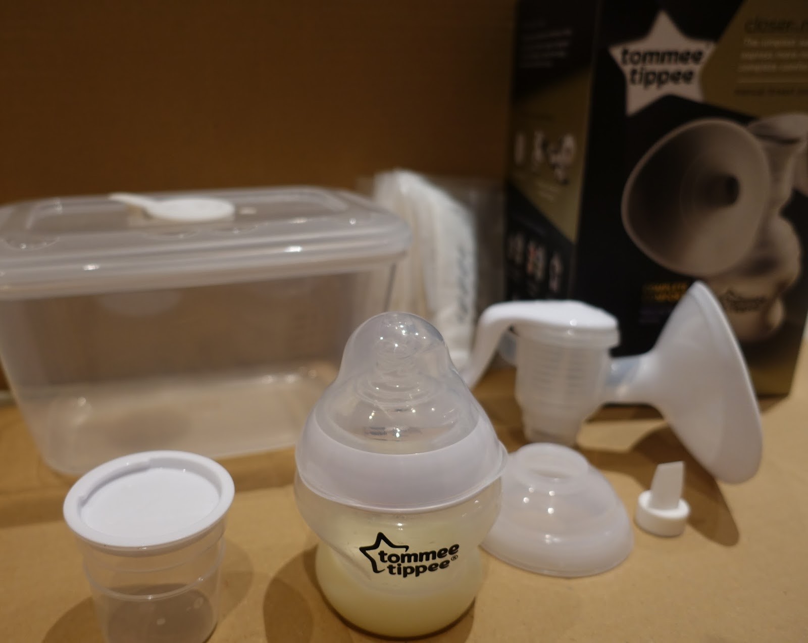 The Tommee Tippee manual breast pump box, the steriliser box, the pump parts, the closer to nature bottle (with breast milk in) , the milk storage pot and disposable breast pads
