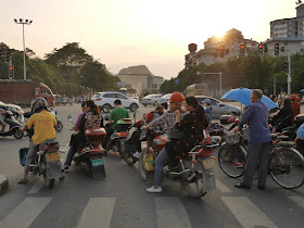 people on motorbikes and bicycles waiting for the light to change at an intersection in Guilin