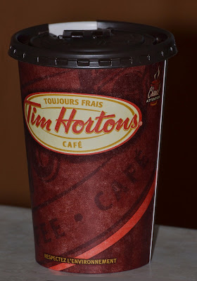A cardboard Tim Hortons coffee cup with plastic lid.