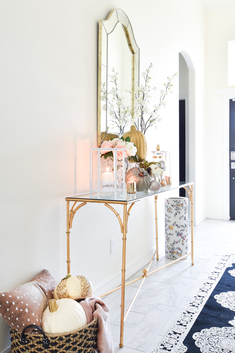 A white foyer goes glam with gold, pink and silver fall decor accents on a bamboo console table. A white foyer goes glam with gold, pink and silver fall decor accents on a bamboo console table.