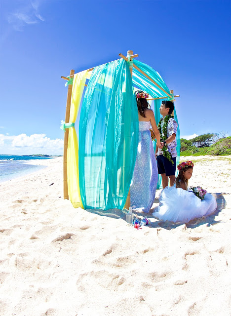 Hawaii beach wedding with under the turquoise and yellow archway with bamboo