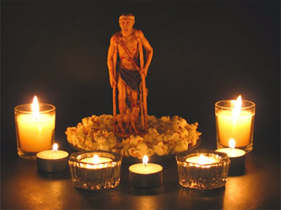La imagen de San Lázaro sobre un plato con palomitas de maiz y velas encendidas