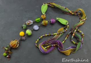 http://earthshine.indiemade.com/product/purple-green-and-gold-mixed-media-artisan-necklace?tid=1