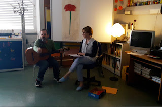 A professora olha para o professor que gesticula a explicar algo.