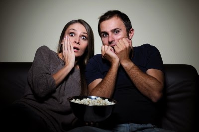 man and woman watching scary show on tv