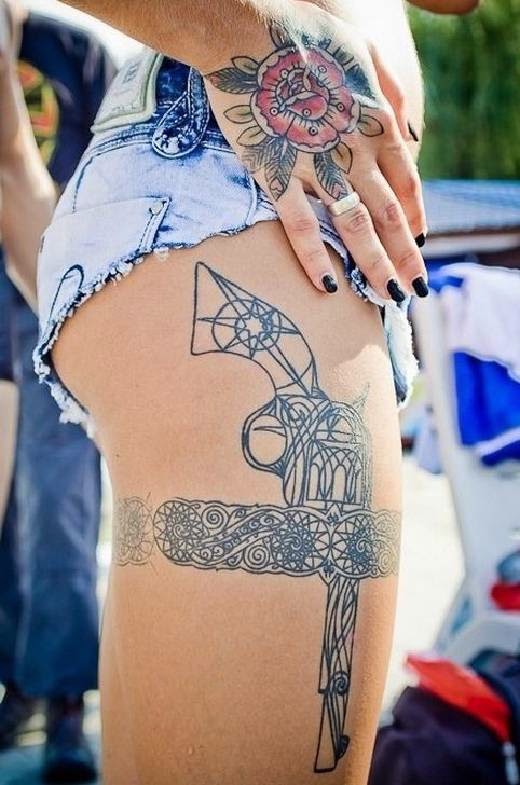 vemos un tatuaje en la pierna de una mujer, es el tatuaje de una pistola y un liguero
