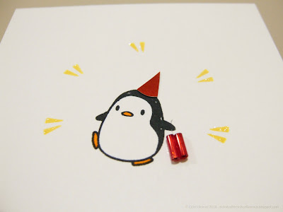 Close up of penguin wearing a party hat and holding a few sticks of dynamite.