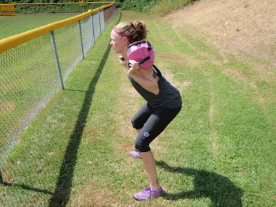 A woman uses the Ultimate Sandbag on her shoulders to perform a squat