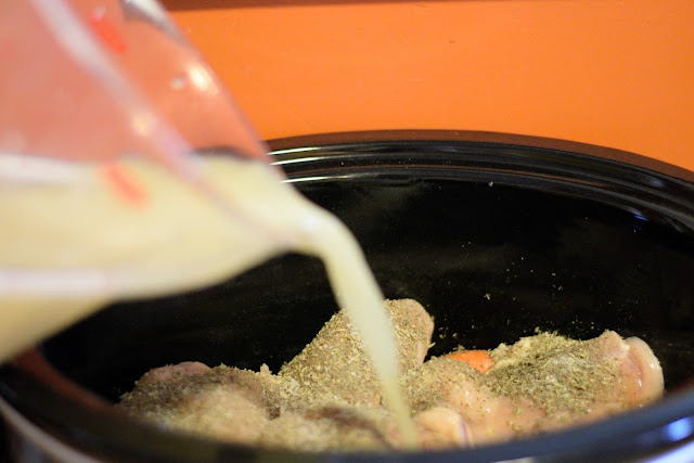 The chicken stock being poured over the chicken in the crock pot