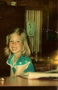 Exquisitely Unremarkable Author as a young girl sitting in the kitchen