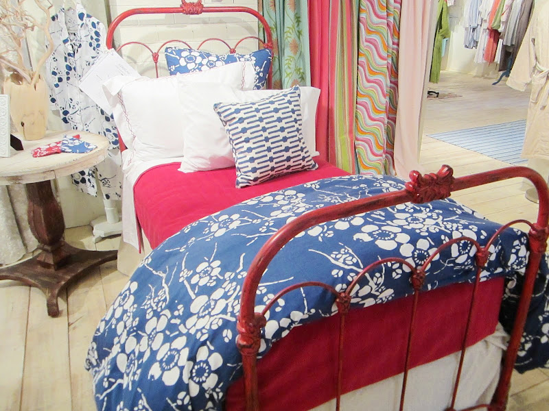 Bed with red iron frame and red, white and blue bedding and pillows