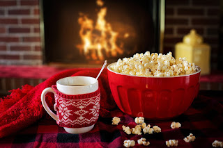 Bowl of popcorn on table in front of a fireplace