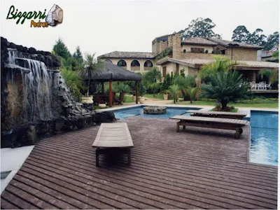 Construção da cascata em piscina com pedras ornamentais com execução do deck de madeira e a execução do paisagismo.