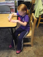 Child sitting crookedly at a table.