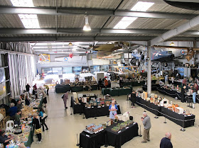View of the sales and display hall of a miniature convention, set in a hangar.