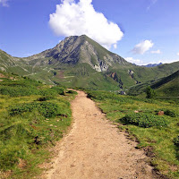 Yeşil bir alanda yüksek bir dağa doğru uzanan patika yol