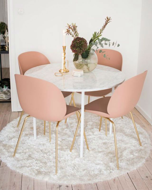 Mesa redonda con tapa de mármol, con sillas color rosa maquillaje con patas doradas