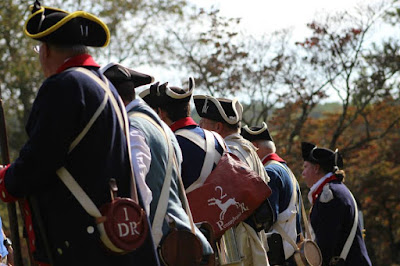 Line of Revolutionary War reenactors with backs to camera Line of Revolutionary War reenactors with backs to camera