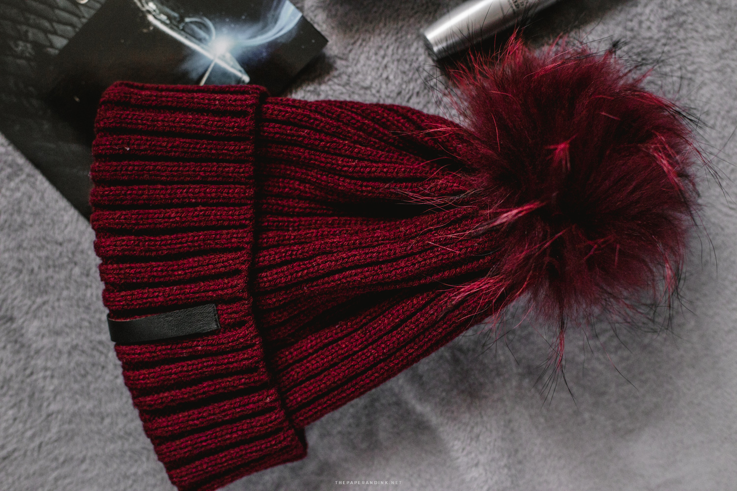 A burgundy beanie with a furry pompom by Cortefiel.