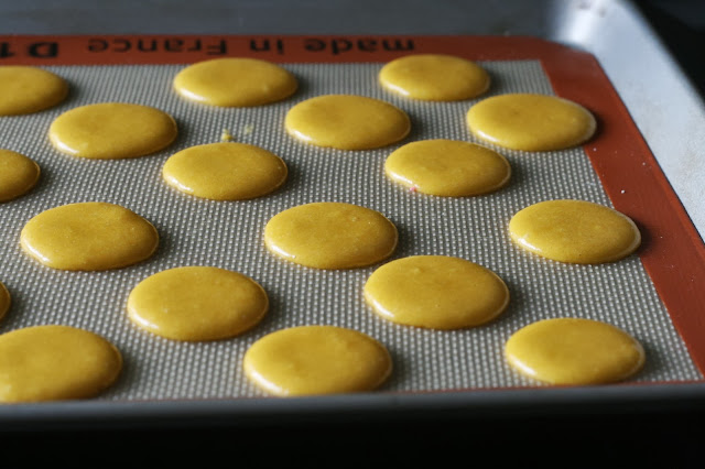 Macaron shells resting on a sheet waiting for a skin to form.