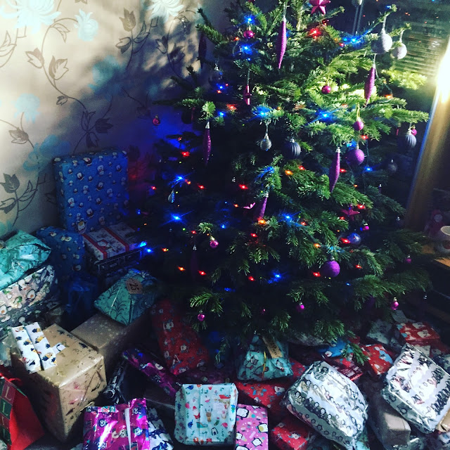 A real decorated christmas tree with wrapped gifts underneath