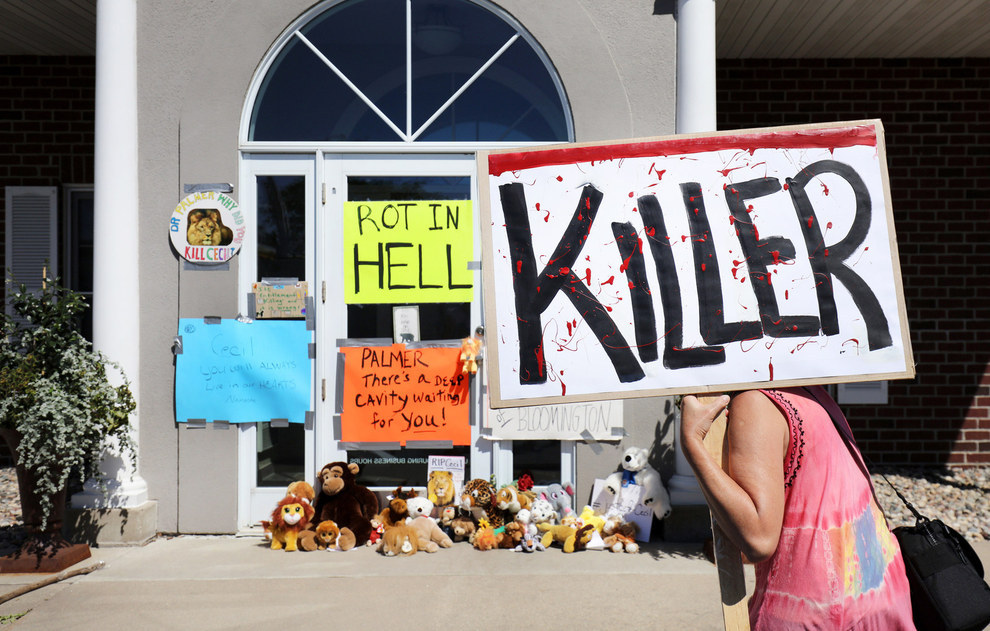 70 Of The Most Touching Photos Taken In 2015 - Protesters denounce the poaching of Cecil the lion, in the parking lot of Dr. Walter Palmer’s River Bluff Dental Clinic in Bloomington, Minnesota.