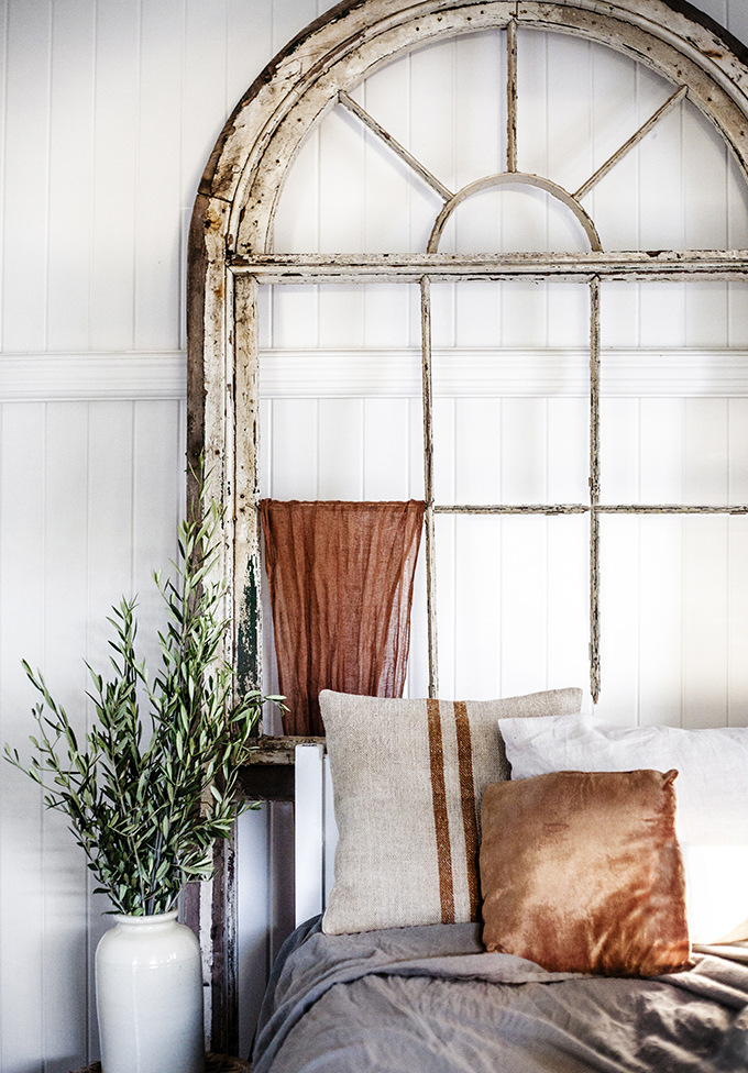 Rustic Bohemian Interior Design in a Bedroom by Kara Rosenlund with salvaged vintage arch window and burnt orange accents. #whitebedroom #vintage #rustic #orange #cottage