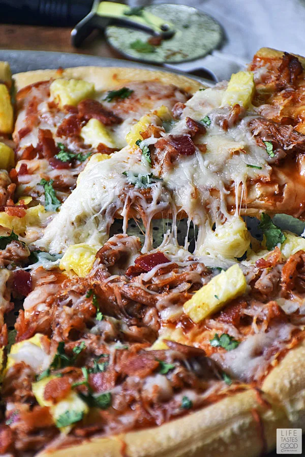 BBQ Pulled Pork Pizza - pulling a slice of pizza up with cheese stretching
