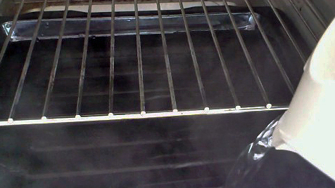 pouring water into baking tray in the oven