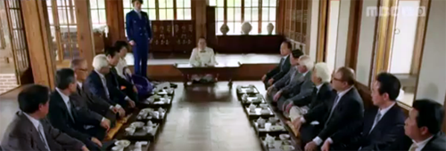 Lee Gun speaks at his family meeting to two rows of executives.