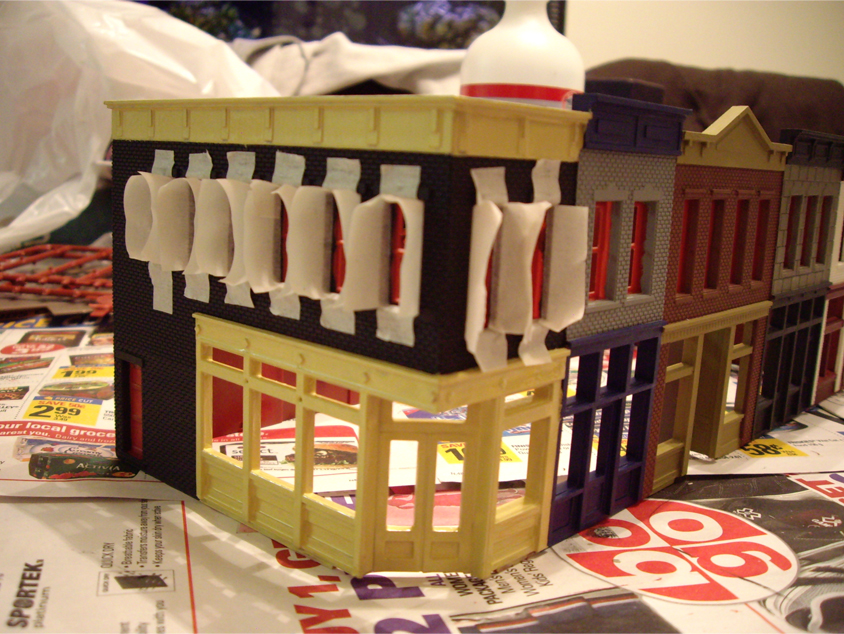 Partially constructed and painted Walthers Merchant’s Row 1 kit with masking tape applied around windows
