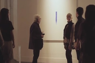 artista explicando su obra una raya azul en la pared
