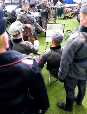 Group of 1/6 scale German soldiers being briefed in a diorama of an army post on display at a scale model exhibition.