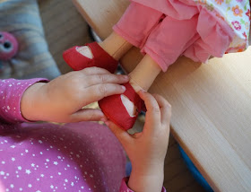Puppen sind unglaublich wichtig für Kinder, als Freunde und Begleiter der Kindheit. Ich stelle Euch die wunderschön gestalteten und kuschelweichen Puppen Milla und Matze von HABA vor, die gerade bei uns eingezogen sind. Hier: Mädchenpuppe Milla beim Schuhe anziehen.