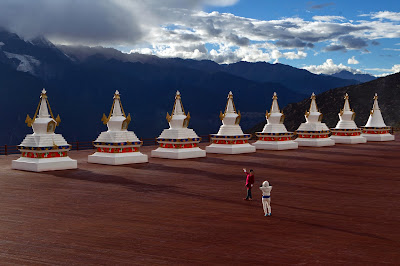 Tourist poses for a picture in front of stupa's and the Meili snow mountain range in Deqen county, Diqing Tibetan Autonomous Prefecture of southwest China's Yunnan Province. The range sacred to Tibetans is home to Yunnan's highest peak, the unclimbed Kawa Garbo at 6740 metres above sea level.