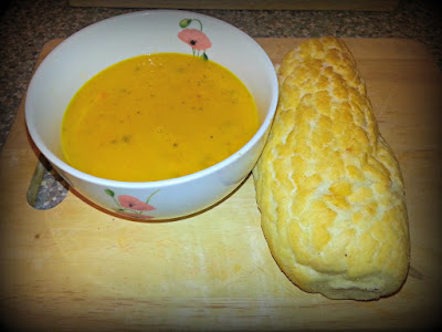 Bowl of carrot soup with bread baton.