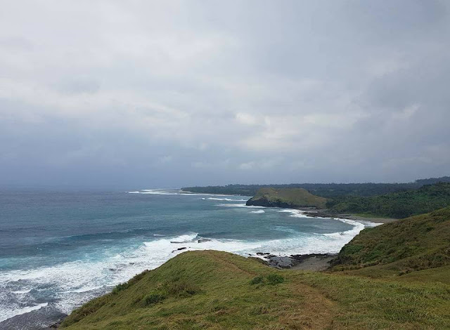 Dark sky, beautiful wave hump in the rocky coastline with green grass
